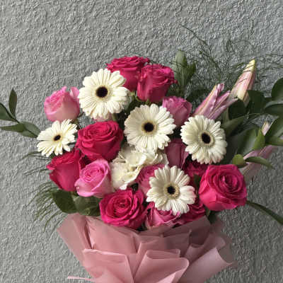 Bouquet of pink roses and white gerbera daisies wrapped in pink paper