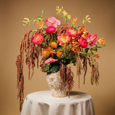 Tall floral arrangement in a textured vase with pink and orange blooms