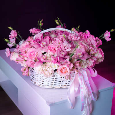 Pink flower basket with roses and orchids in a white wicker basket