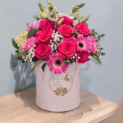 Pink roses and gerbera daisies arranged in a round hatbox