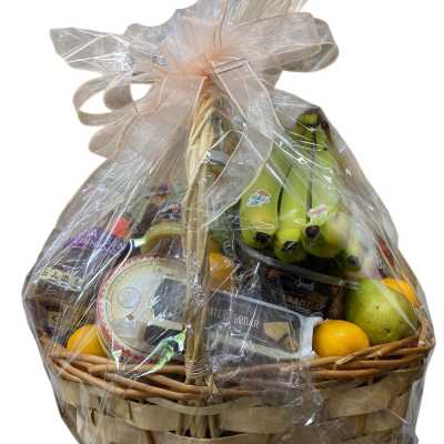 Gift basket with fruit, wine, and snacks wrapped in clear plastic