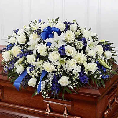 White and blue floral casket spray with ribbon accents