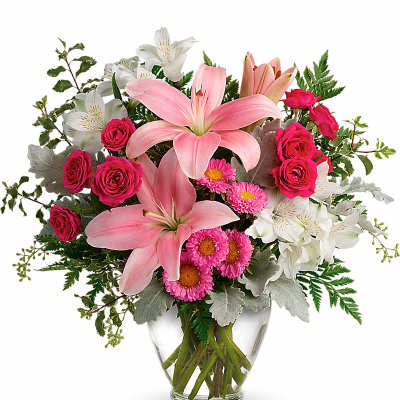 Mixed arrangement of pink lilies, bright pink roses, and white alstroemeria in a clear glass vase