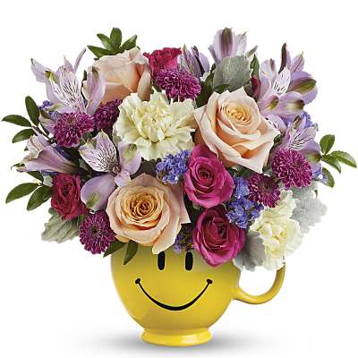 Colorful mix of pink and peach roses with carnations in a yellow smiley face mug