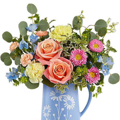 Colorful bouquet of roses, carnations and mums in a light blue daisy-print ceramic pitcher.