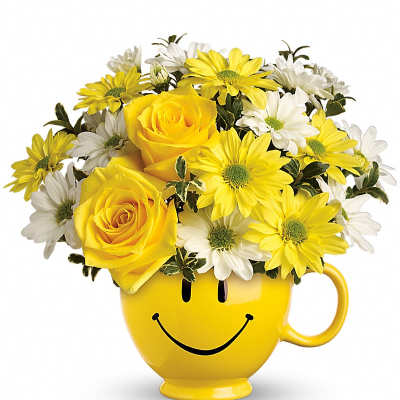 Yellow roses and white daisies arranged in a yellow smiley-face mug