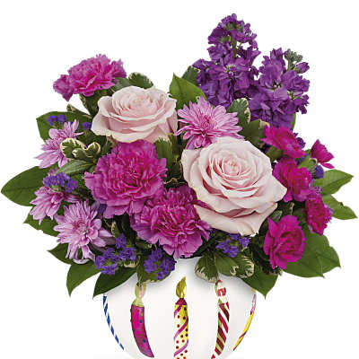 Pink and purple mixed flower arrangement in a white bowl with painted birthday candles
