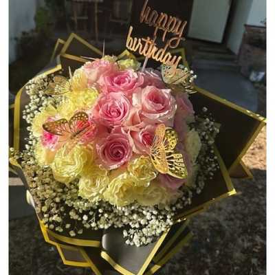 Birthday bouquet of pink and yellow roses with baby's breath, butterflies, and a happy birthday topper