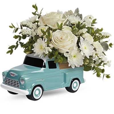 White roses and mums arranged in a light blue ceramic vintage truck container