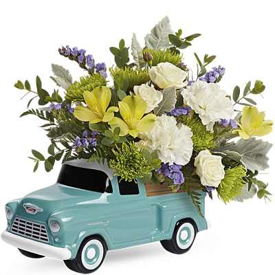 White, yellow, and green mixed flowers arranged in a turquoise ceramic pickup truck container