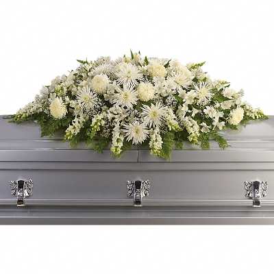 White casket spray of chrysanthemums and other flowers on a gray casket