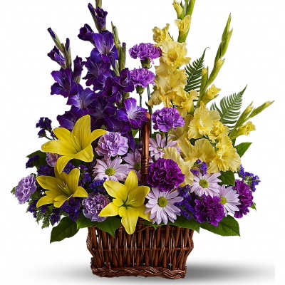 Tall wicker basket arrangement with purple and yellow flowers including lilies, daisies, and carnations