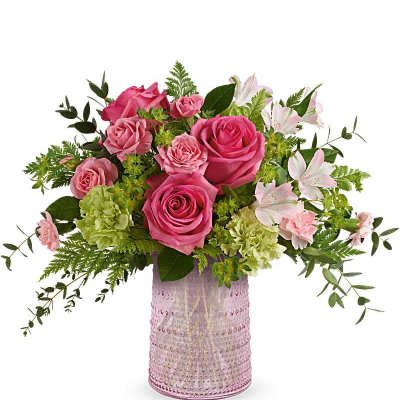 Pink roses, green carnations, and pale pink blooms arranged in a pink textured glass vase