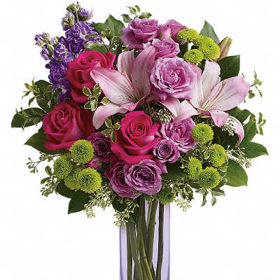 Tall pink and purple bouquet with roses, lilies, and green button poms in a slim lavender glass vase