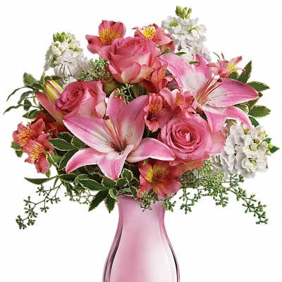 Pink lilies, roses, and white flowers arranged in a pink glass vase