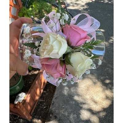 Pink and white rose wrist corsage with small white blooms and pink ribbon on a clear band