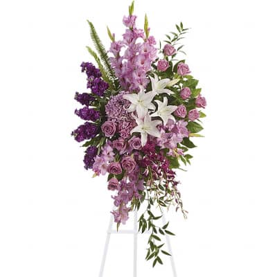 Tall lavender and white standing spray with lilies, roses, and hydrangea on a white easel