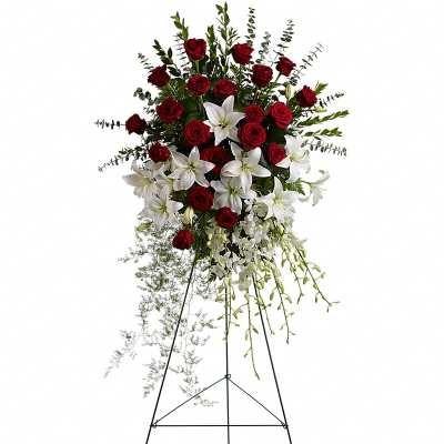 Standing spray of red roses and white lilies with cascading white orchids on a metal easel.