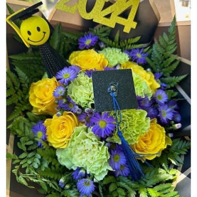 Graduation bouquet with yellow roses, green carnations, purple asters and grad-themed picks reading 2024.