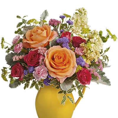Bright mixed bouquet of orange and pink roses with purple accents in a yellow ceramic pitcher