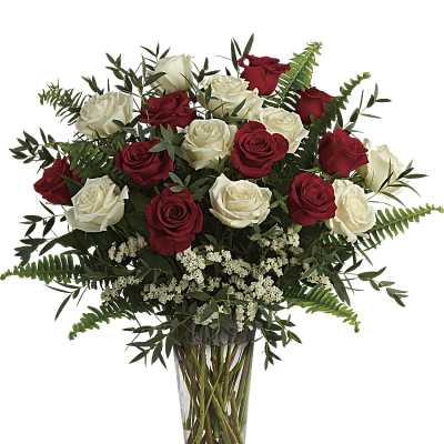 Tall clear vase of red and white roses with small white filler flowers