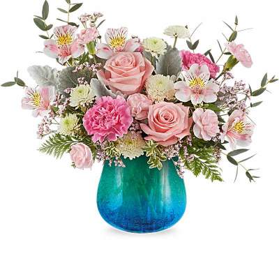 Pink roses, carnations, and mixed flowers arranged in a teal-blue glass vase