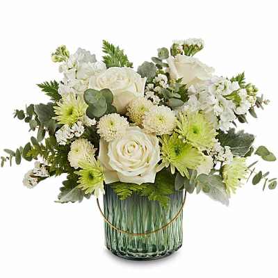 Low arrangement of white roses and mums with pale green accents in a ribbed green glass vase