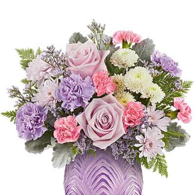 Pastel arrangement of pink roses, carnations, and white mums in a lavender textured glass vase