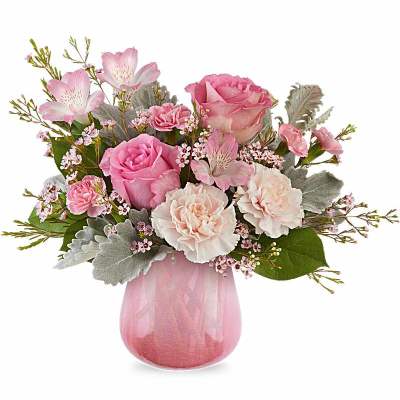 Pink and white roses, carnations, and alstroemeria arranged in a pink glass vase