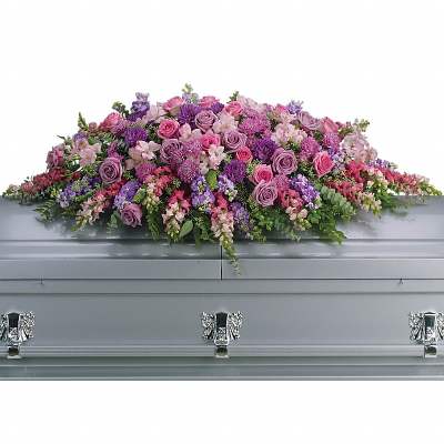 Large pink and purple casket spray with roses and other flowers on a silver casket
