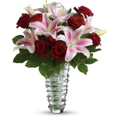 Red roses and pink lilies arranged in a clear glass vase.