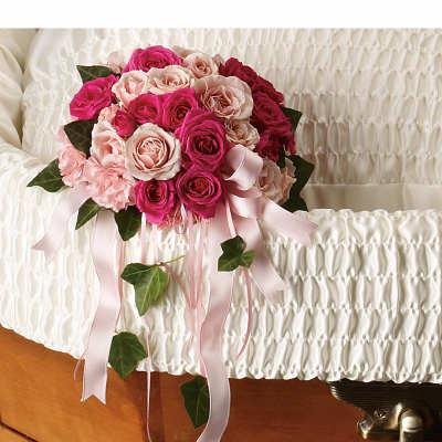 Pink and hot pink rose cluster with ribbons on white casket interior with trailing ivy