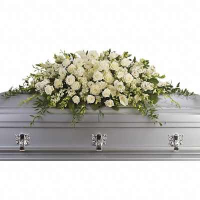 Long white rose and calla lily casket spray arranged on top of a silver casket