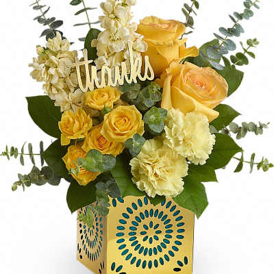 Yellow roses and carnations in a yellow patterned cube vase with a 'thanks' pick