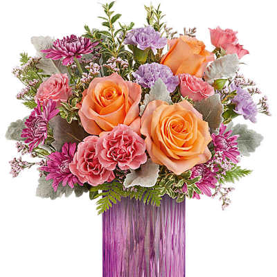 Mixed bouquet of peach roses and pink and purple flowers in a tall purple glass vase