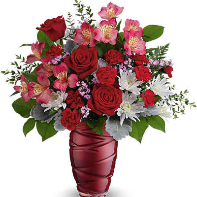 Mixed bouquet of red roses, carnations, pink alstroemeria, and white mums in a red glass vase