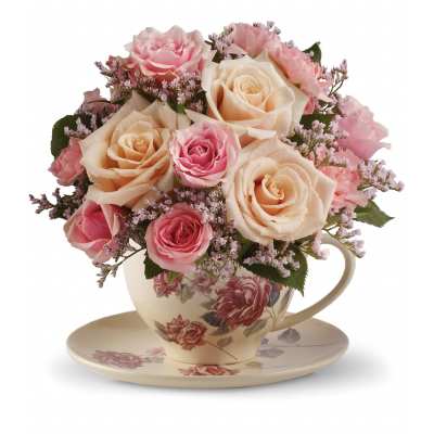 Arrangement of pink and peach roses in a floral teacup on a matching saucer
