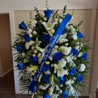 Large blue and white funeral spray on an easel with a ribbon