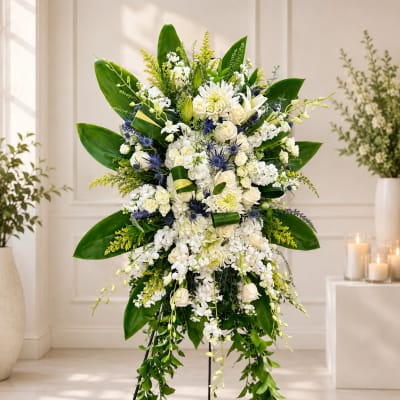 Large white floral standing spray with green leaves and blue accents
