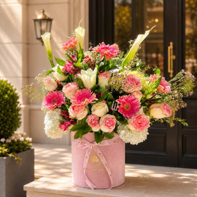 Pink and white mixed flower arrangement in a round pink box