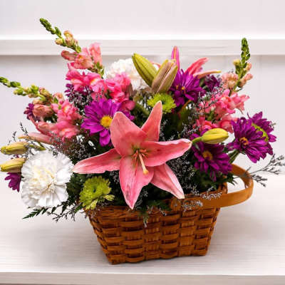 Basket arrangement with pink lilies, purple daisies, and white carnations