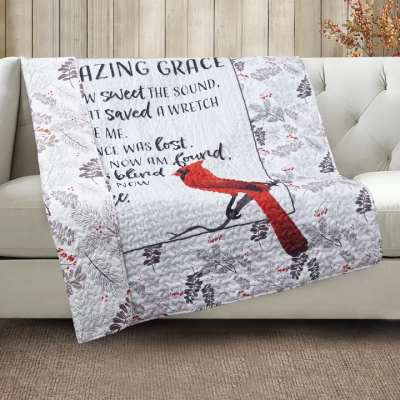 Quilted throw blanket with a red bird and printed text draped over a sofa