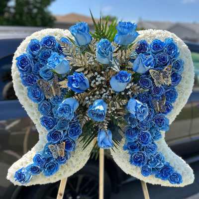 Blue rose funeral spray in a butterfly shape on an easel