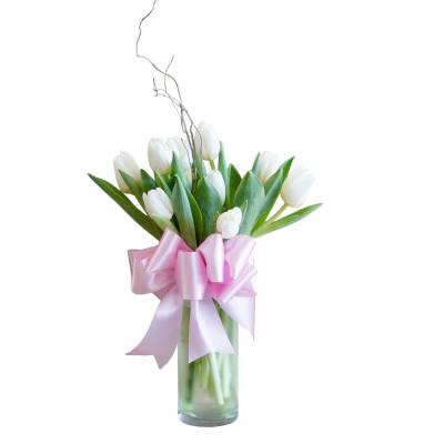 White tulips in a clear glass vase with a pink ribbon bow