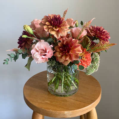 Mixed pink and peach flowers arranged in a clear glass vase