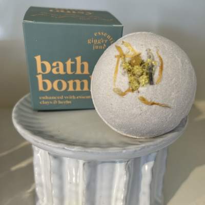 Bath bomb on a ceramic pedestal with its box behind it