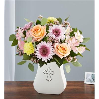 Mixed bouquet of roses and daisies in a white vase with a cross