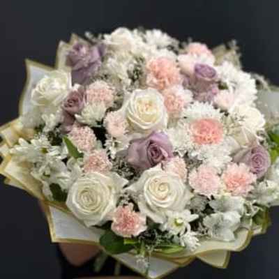 Bouquet of white, blush, and lavender roses with small white flowers