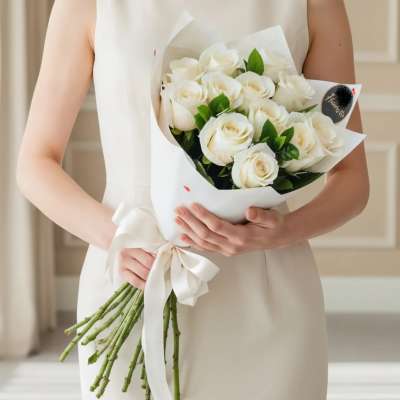 Woman holding a bouquet of white roses wrapped in white paper