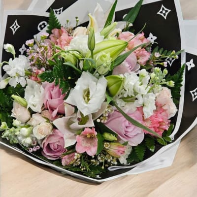Bouquet of pink and white flowers wrapped in black paper
